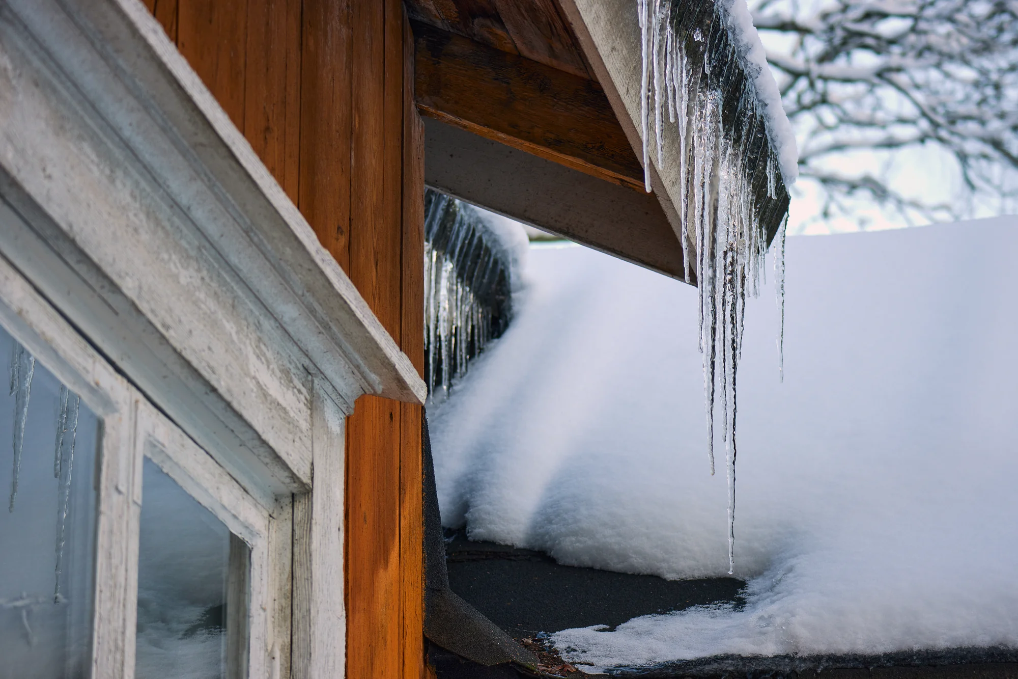 Ice dam and icicles on a snow-covered roof edge in Woodbury, MN