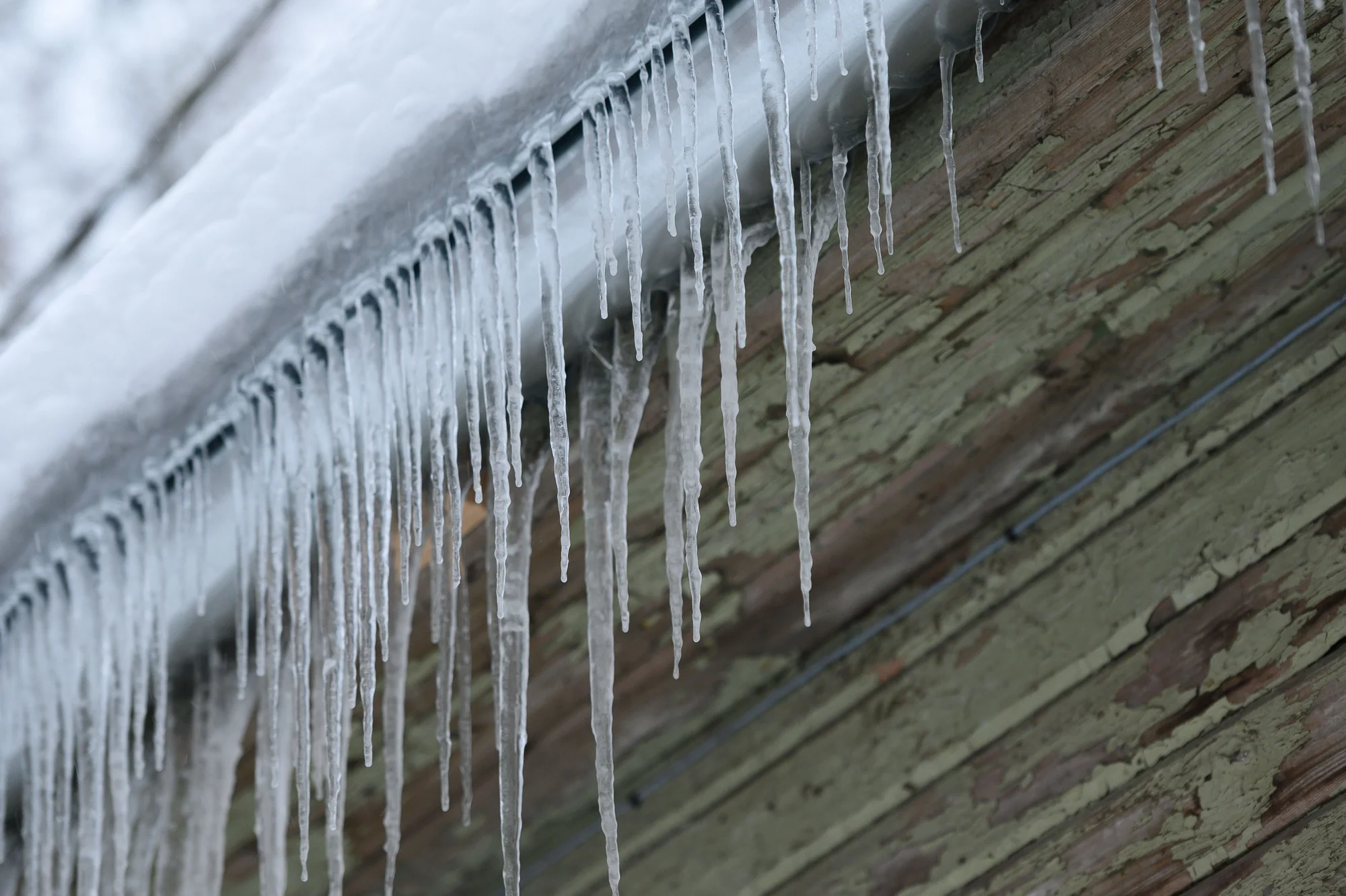 Row of icicles along a roof gutter needing ice dam removal in Oakdale, MN