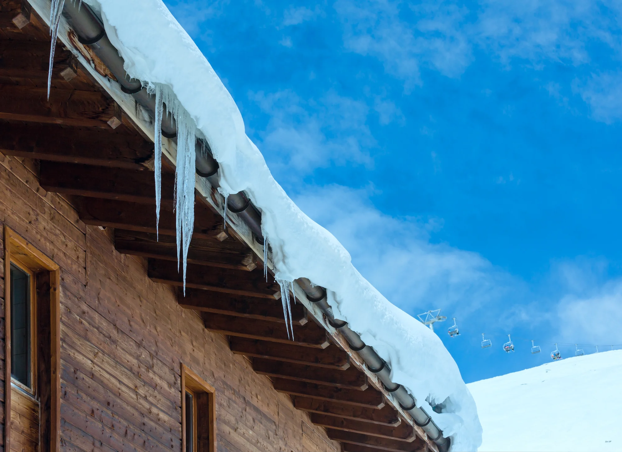Snow and icicles built up on a roof edge against a blue sky in Woodbury, MN
